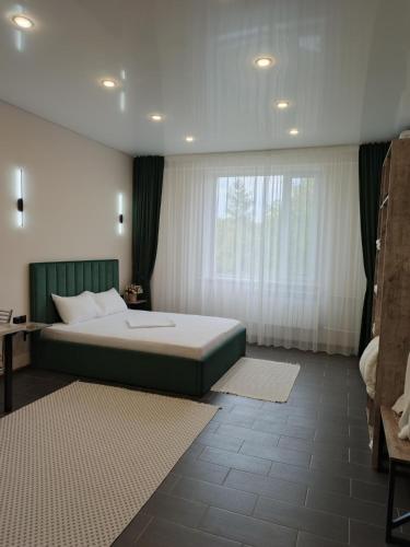 a bedroom with a large bed and a window at Berloga Hotel in Pavlodar