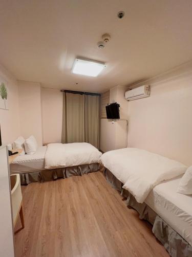 a room with three beds and a television in it at Whouse-sinchon in Seoul