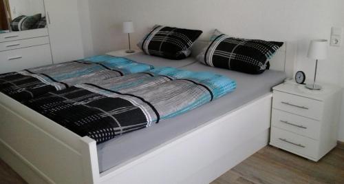 a white bed with black and blue sheets and pillows at Ferienwohnung Hunold in Marsberg