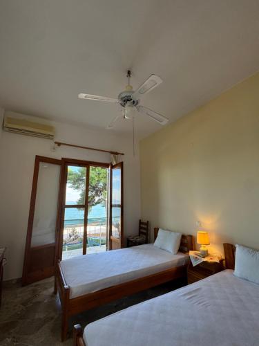 a bedroom with two beds and a ceiling fan at Cherronisi Apartments in Áyios Andréas
