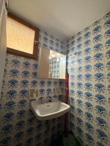 a bathroom with blue and white tiled walls and a sink at Cherronisi Apartments in Áyios Andréas