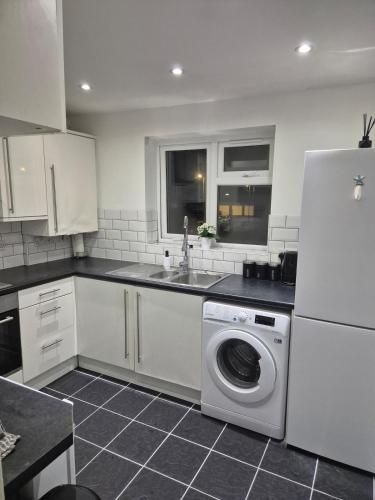 a kitchen with a washing machine and a sink at 5 min from airport, luxury 2 bed apartment in Luton