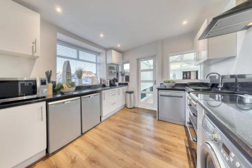 a kitchen with white cabinets and a wooden floor at Bakers House - 4 Bedrooms - Parking for 3 cars - Dogs welcome in Wells next the Sea