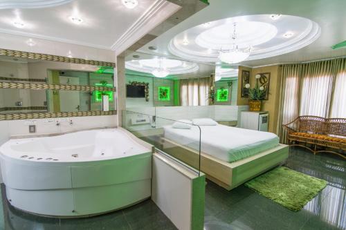 a large bathroom with a tub and a bed at Golden Motel Diária suítes amplas, conforto premium e total privacidade in Passo Fundo