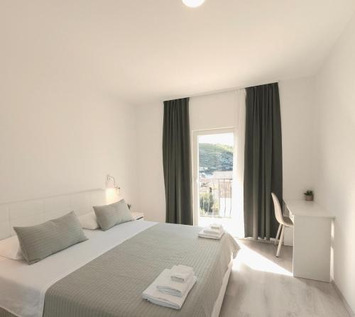 a white bedroom with a bed and a window at 3-bedroom Sea View Home with Private Parking in Mokošica