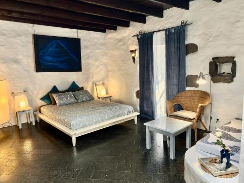 een slaapkamer met een bed en een stoel bij Stylish getaway with secluded Patio in lava Finca in Uga