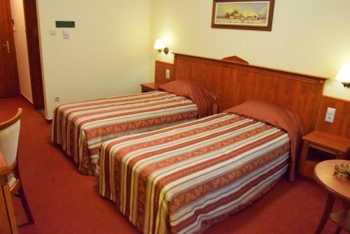 a hotel room with two beds and a table at Geréby Kúria Hotel és Lovasudvar in Lajosmizse