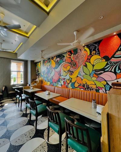 a restaurant with tables and chairs and a colorful wall at Hotel Atlantiis Suites Near Kashi Vishwanath temple in Varanasi