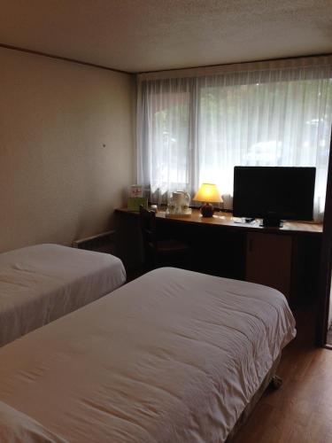 a hotel room with two beds and a desk with a computer at Campanile Mulhouse - Illzach Ile Napoléon in Illzach