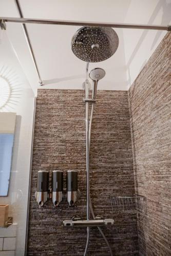 a shower in a bathroom with a brick wall at Bela Vista Burgau in Burgau