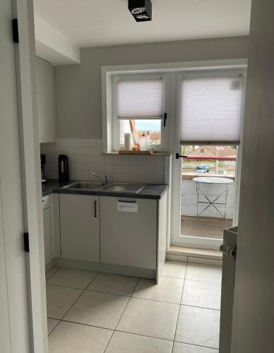 a kitchen with a sink and a window at Residentie Sofie in Koksijde