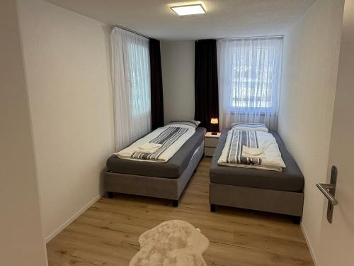 two beds in a small room with a window at Deine Auszeit mit Alpenblick in Kandergrund