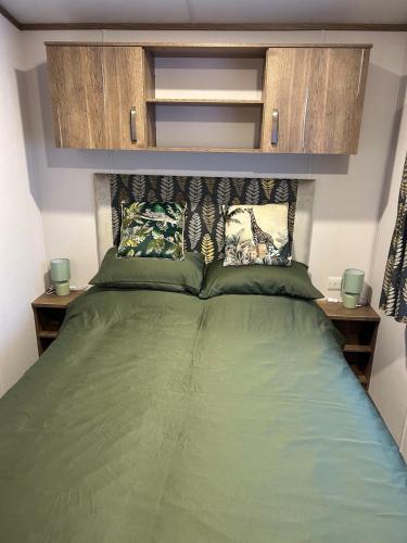 a bedroom with a green bed with wooden cabinets at Annas Escape Burnside Moray in Fochabers