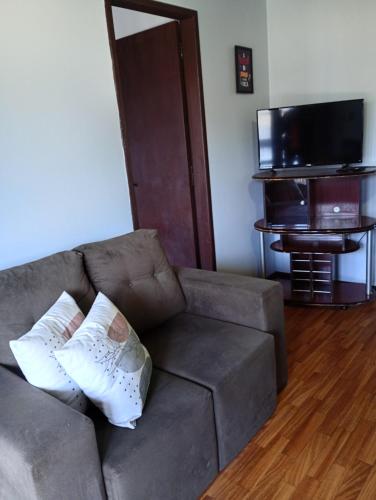 a living room with a couch and a flat screen tv at Aluguel de Temporada in Arroio do Sal