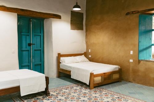 a bedroom with two beds and a blue door at Posada Los Tres Arrieros in Jordán