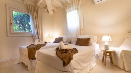 a bedroom with two beds with white sheets and a window at Villa Sara - Porto Cervo - 2 Private Beaches & Garden - by Coral Property in Porto Cervo