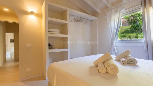 a bedroom with a white bed with towels on it at Villa Sara - Porto Cervo - 2 Private Beaches & Garden - by Coral Property in Porto Cervo