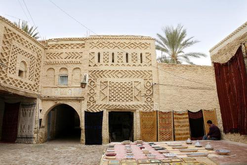 un uomo seduto davanti a un edificio di appartement Tozeur médina a Tozeur