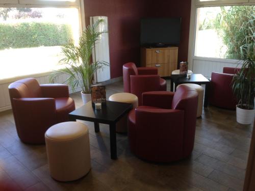 a waiting room with chairs and tables and a tv at Campanile Mulhouse - Illzach Ile Napoléon in Illzach