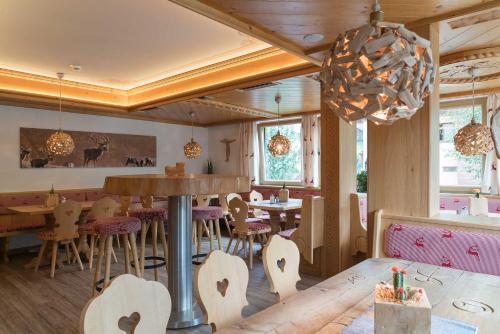 a restaurant with tables and chairs and a chandelier at Atelier Garni Astei in Grossarl
