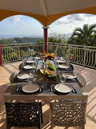a table with glasses and plates on a balcony at Villa CosaRoé-Vue Mer-Piscine-3 étoiles in Rivière-Salée