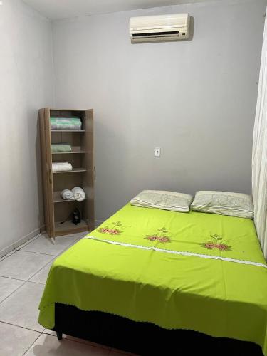 a bedroom with a bed with a green blanket at Casa in São Raimundo Nonato
