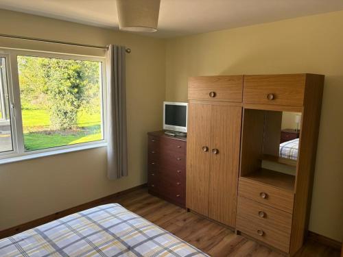 a bedroom with a bed and a dresser and a window at Orchard Cottage in Loughgall