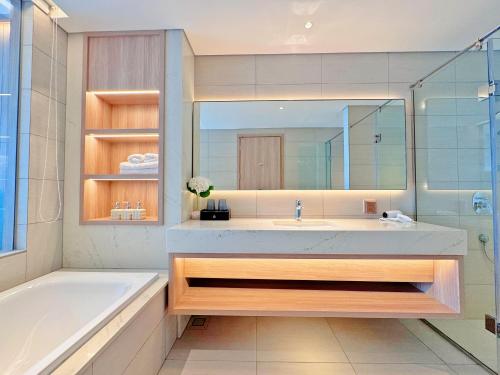 een badkamer met een bad, een wastafel, een bad en een spiegel bij SamSet Corner Seaview Studio A La Carte Ha Long Bay in Ha Long