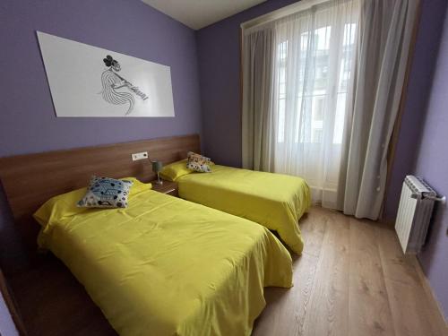 two beds in a room with yellow sheets at El Arca de Noé in Luarca