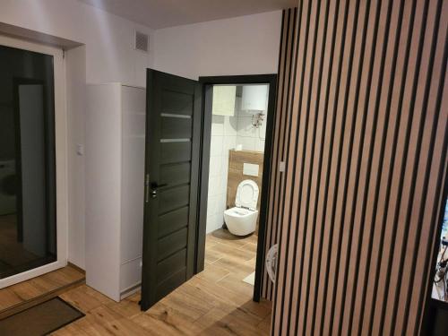 a bathroom with a toilet and a black door at Agrobiskupin Kaczmarek in Gąsawa