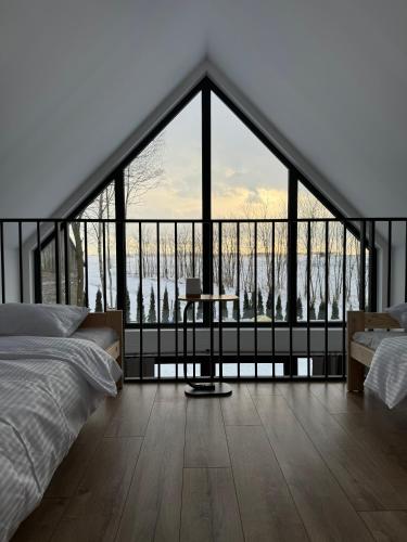 a bedroom with a large window with a bed and a table at Stodoła Parysa in Wola Korytnicka