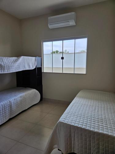 a bedroom with two beds and a window at Aconchego e paz in Rondonópolis