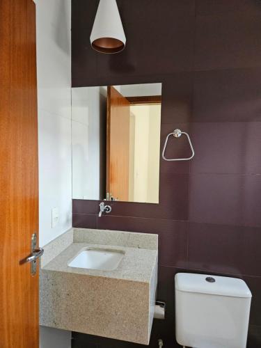 a bathroom with a sink and a toilet and a mirror at Aconchego e paz in Rondonópolis