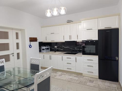 a kitchen with a glass table and a black refrigerator at Zafir Apartment in Korçë