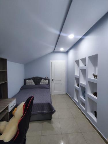 a bedroom with a bed and a desk and shelves at Zafir Apartment in Korçë