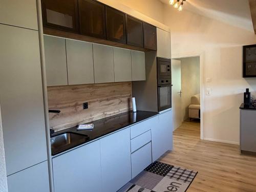 a kitchen with white cabinets and a sink at Deine Auszeit mit Alpen- und Kanderblick in Kandergrund