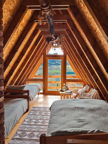 a attic bedroom with three beds and a large window at Vikendica Pino in Han Pijesak