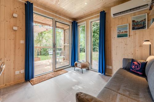 a living room with blue curtains and a couch at Le KuboLodge - Tiny House premium in Jacou