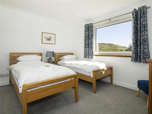 two beds in a room with a window at Dalriada in Portree