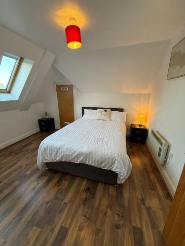 a bedroom with a white bed and wooden floors at Guildford Court Apartment Colchester in Colchester