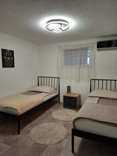 een kamer met twee bedden, een tafel en een raam bij Fly & Stay Apartments in Laktaši