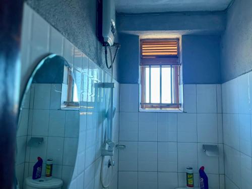 a blue bathroom with a toilet and a window at Stylish Smart Studio Apartment in Kampala