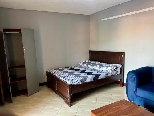 a bedroom with a bed and a blue couch at Stylish Smart Studio Apartment in Kampala