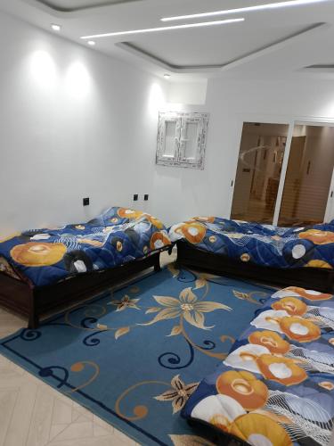 Adel Summer Annaba في عنابة: سريرين في غرفة مع سجادة زرقاء