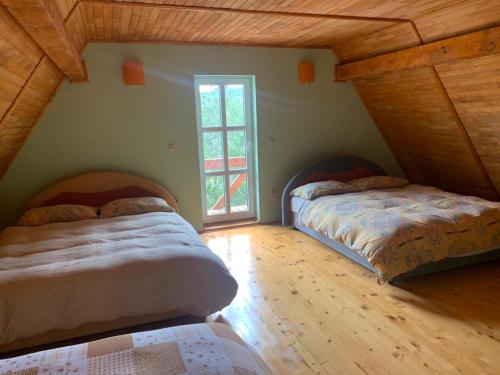 two beds in a attic room with a window at Vikendica PEPO in Blidinje