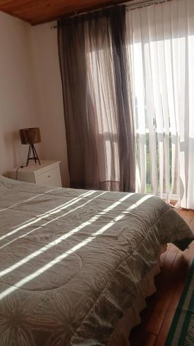 ein Schlafzimmer mit einem großen Bett und einem Fenster in der Unterkunft Družina Embalse Calamuchita in Embalse