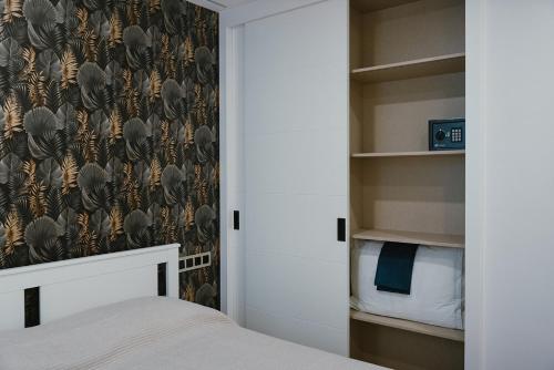 a bedroom with a closet with a bed and a wallpaper at Seba Deluxe Home in Puerto de Santiago