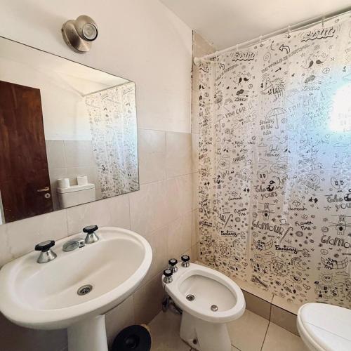 a bathroom with a sink and a toilet and a mirror at Alojamiento Goos in Puerto Pirámides