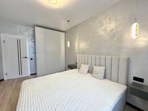 a bedroom with a large white bed with two pillows at Central Park Apart Irpin in Irpin