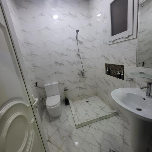 a white bathroom with a toilet and a sink at Pearl Studio Apartments in Abu Dhabi